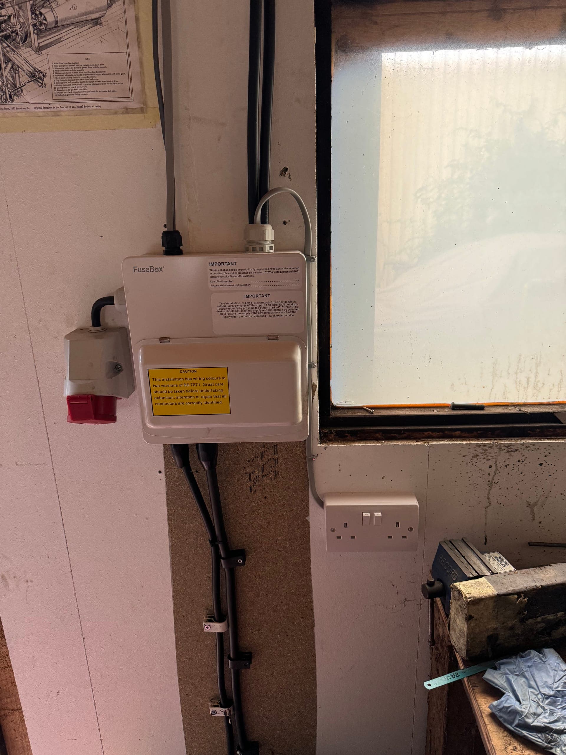 Workshop consumer unit beside a red industrial socket and a twin socket, wired in surface conduit