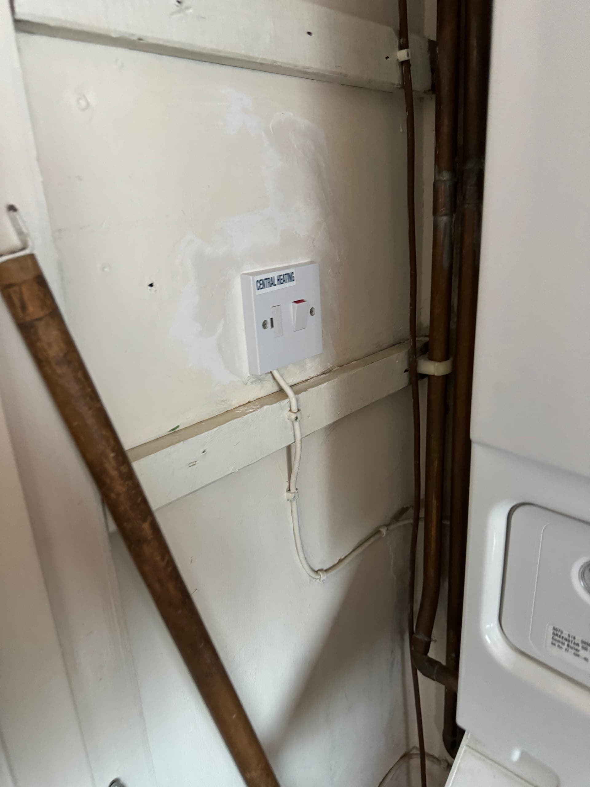 Fused connection unit labelled Central Heating, fitted in an airing cupboard beside the boiler pipework
