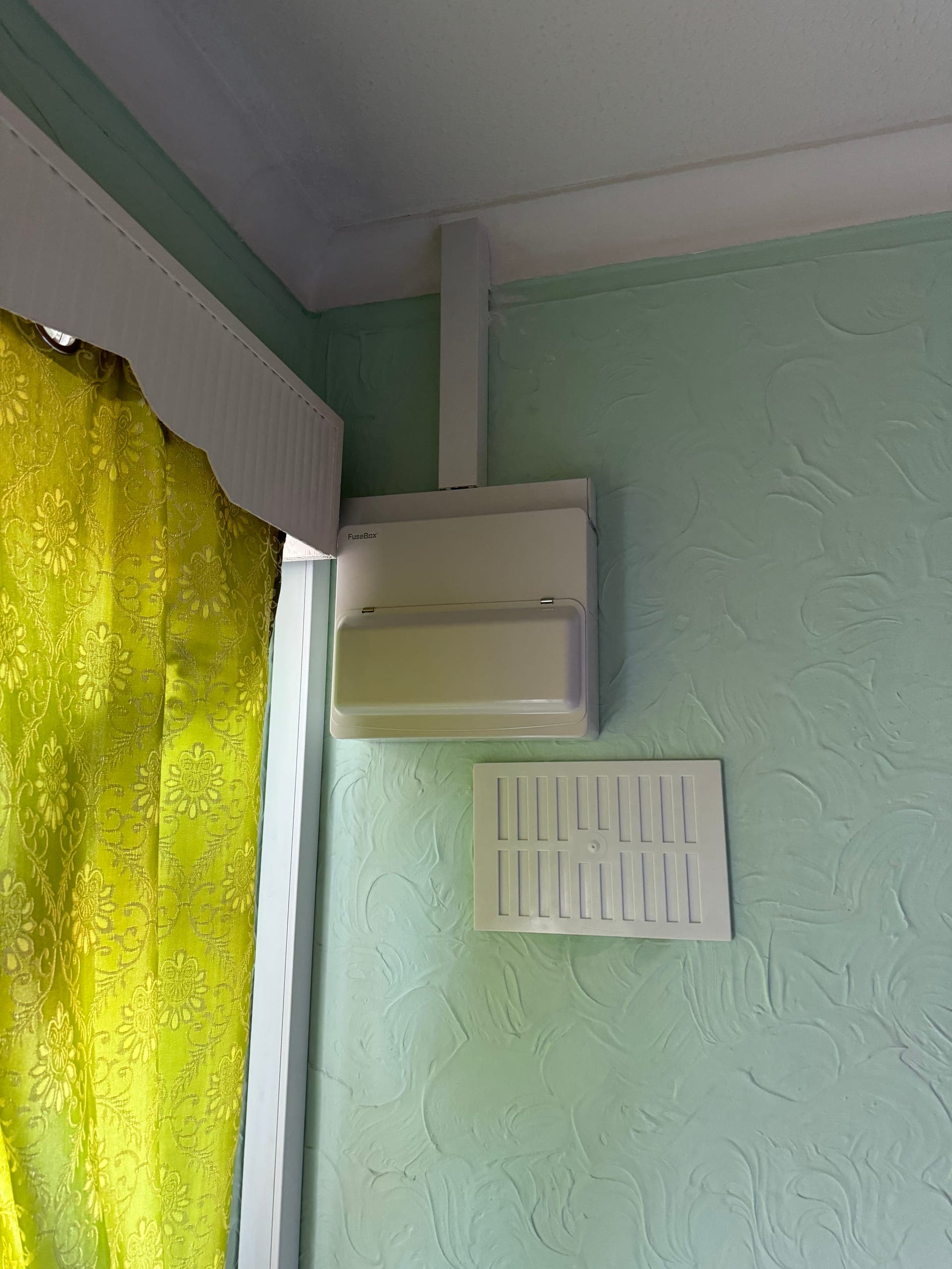Consumer unit mounted high in the corner of a room, fed through surface trunking