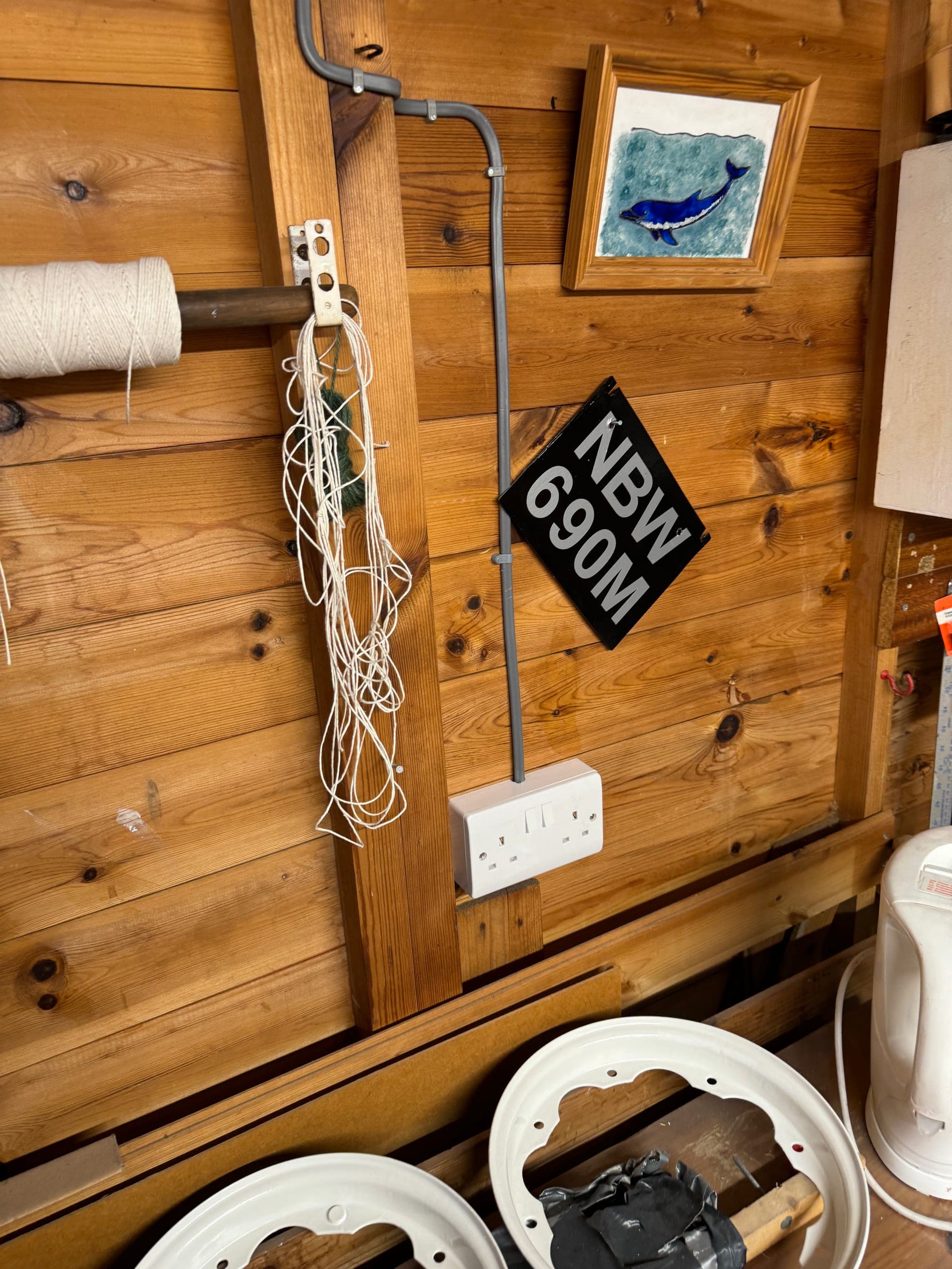 Twin socket on a timber batten in a workshop, fed by surface conduit