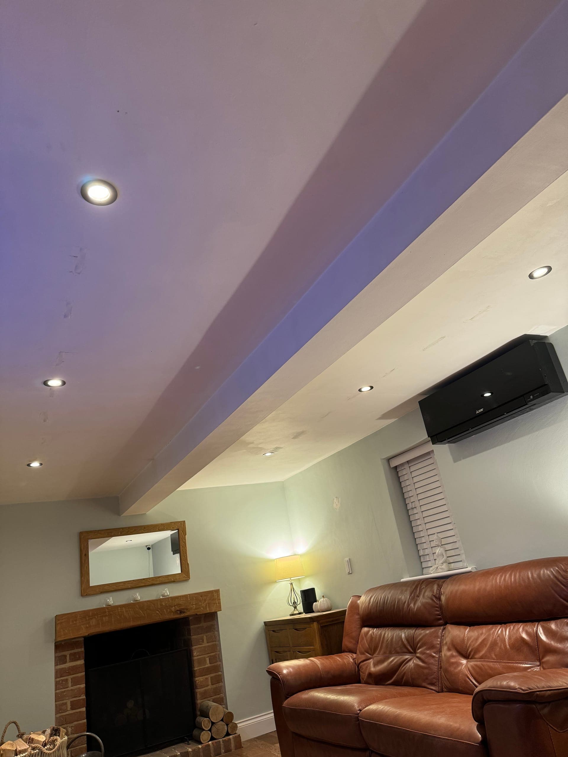 Dropped ceiling detail showing the cove lighting washing the ceiling and downlights over a brick fireplace